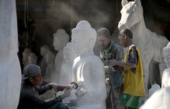 Craftsmen work on Buddha statues at workshop in Myanmar